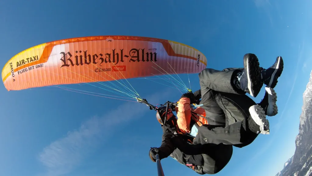 Tandem-Gleitschirm im Flug mit großflächiger Sponsor-Beschriftung